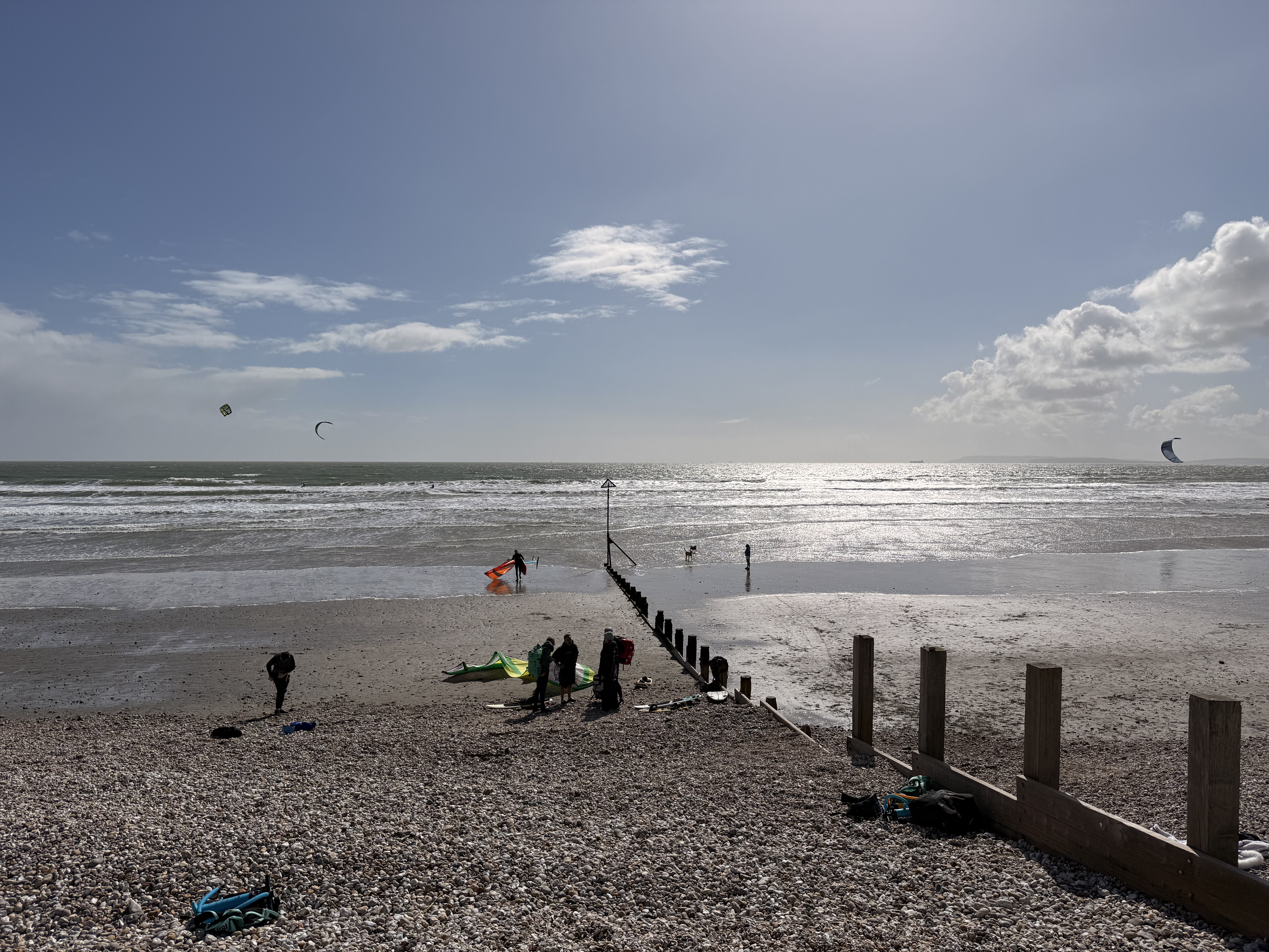 Wide view of East Wittering beach with multiple kites flying