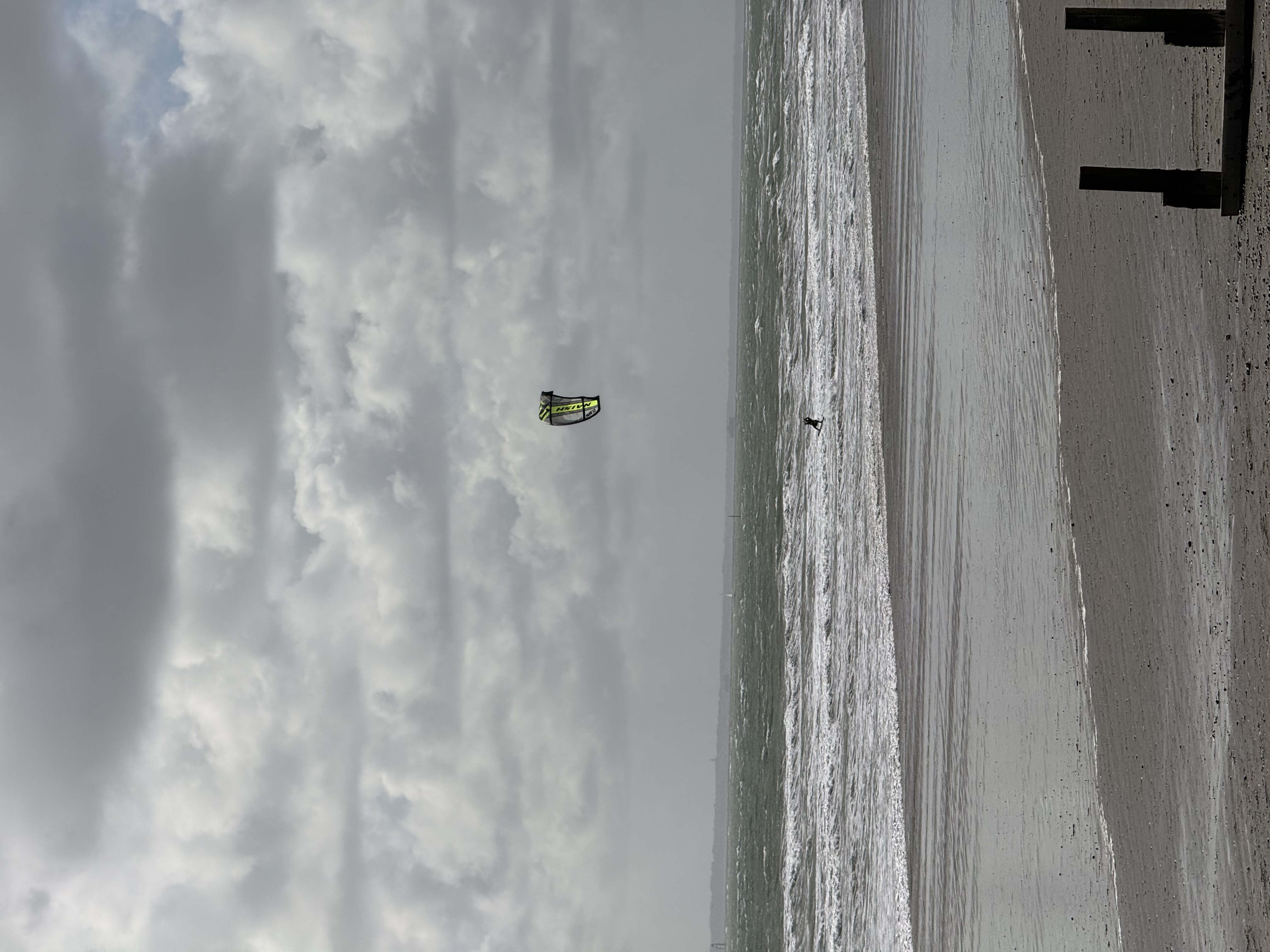 Kite surfer riding waves under a dramatic grey sky