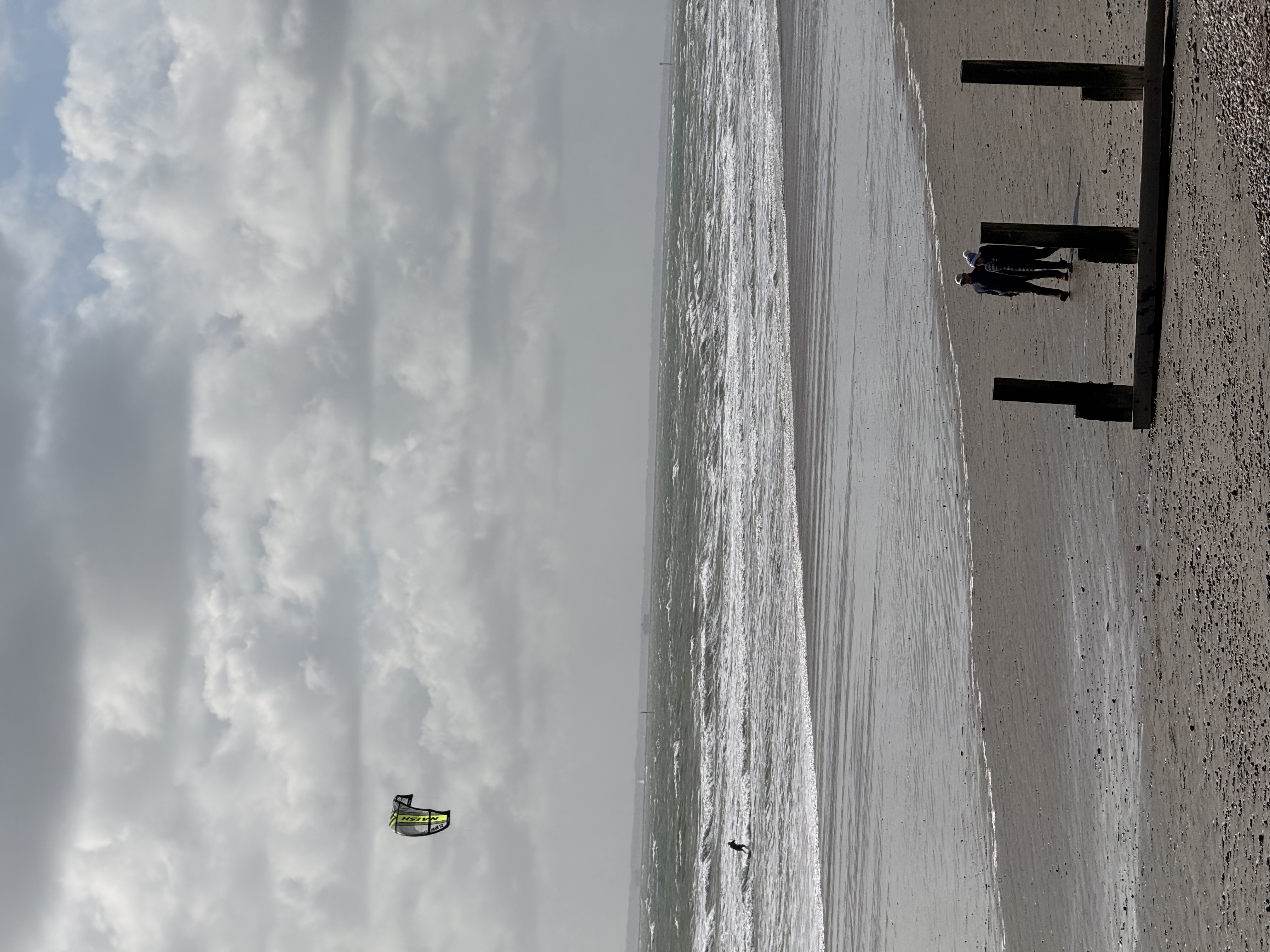 Kite surfer on the water with spectators on the beach