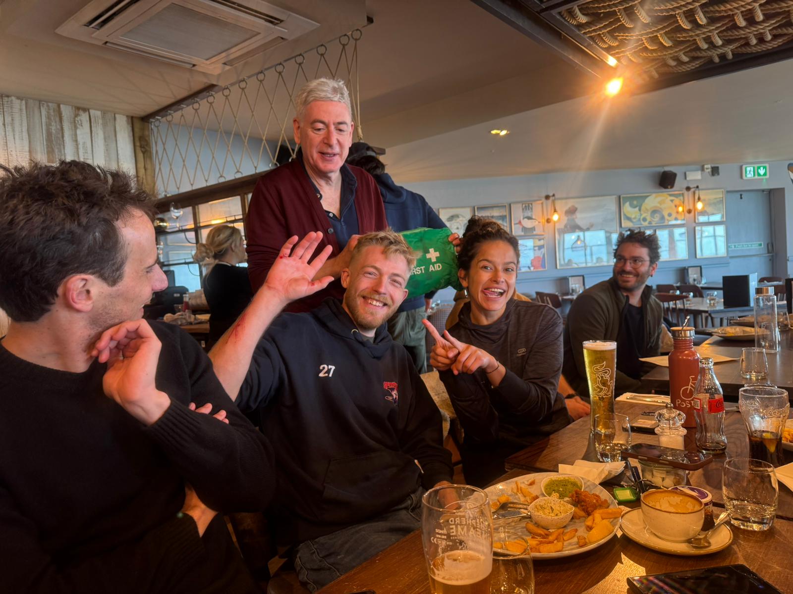 LKSA crew in the pub after the Minnis Bay squall — first aid kit out, a few scrapes being cleaned up, food and beers on the table, everyone smiling